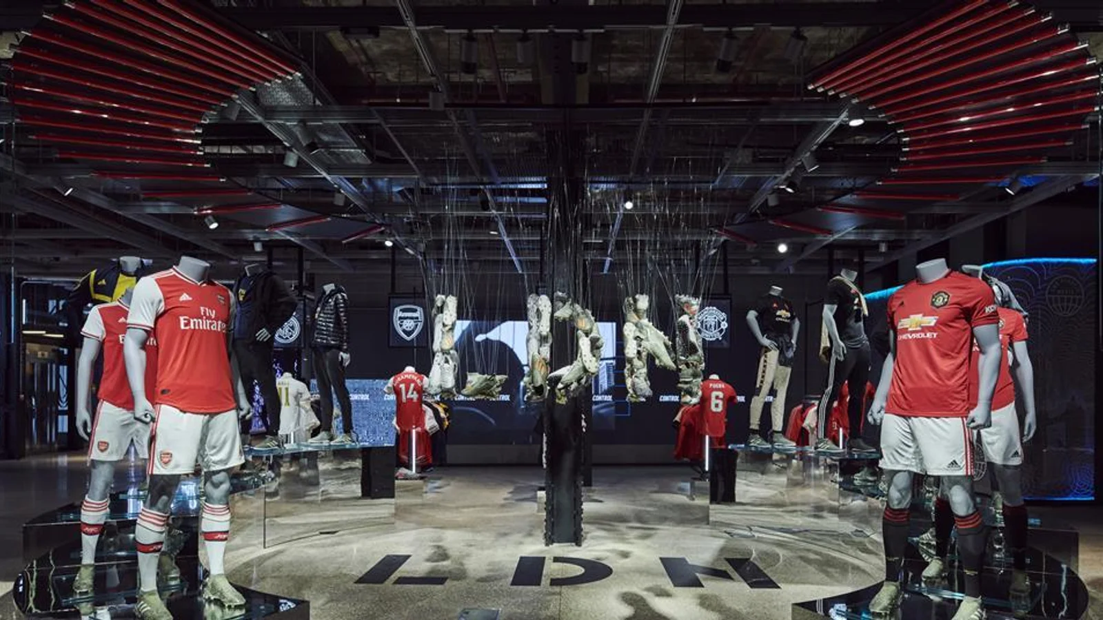 adidas LDN flagship interior on Oxford Street, football shirt displays beneath overhead digital screens