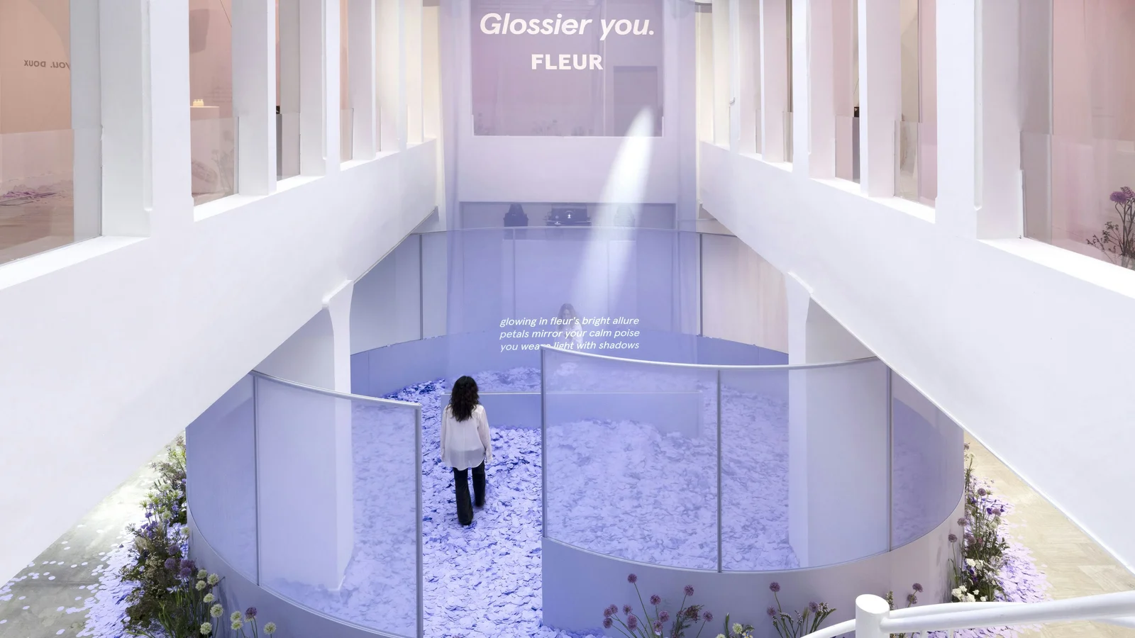 Glossier Fleur launch pavilion in Paris, projection-mapped text on a fabric wall with a visitor silhouette