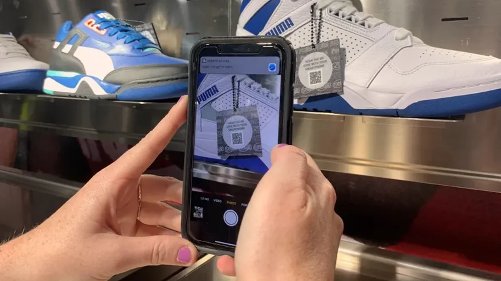 A shopper pointing a phone at PUMA sneakers in the Fifth Avenue flagship to trigger AR product content
